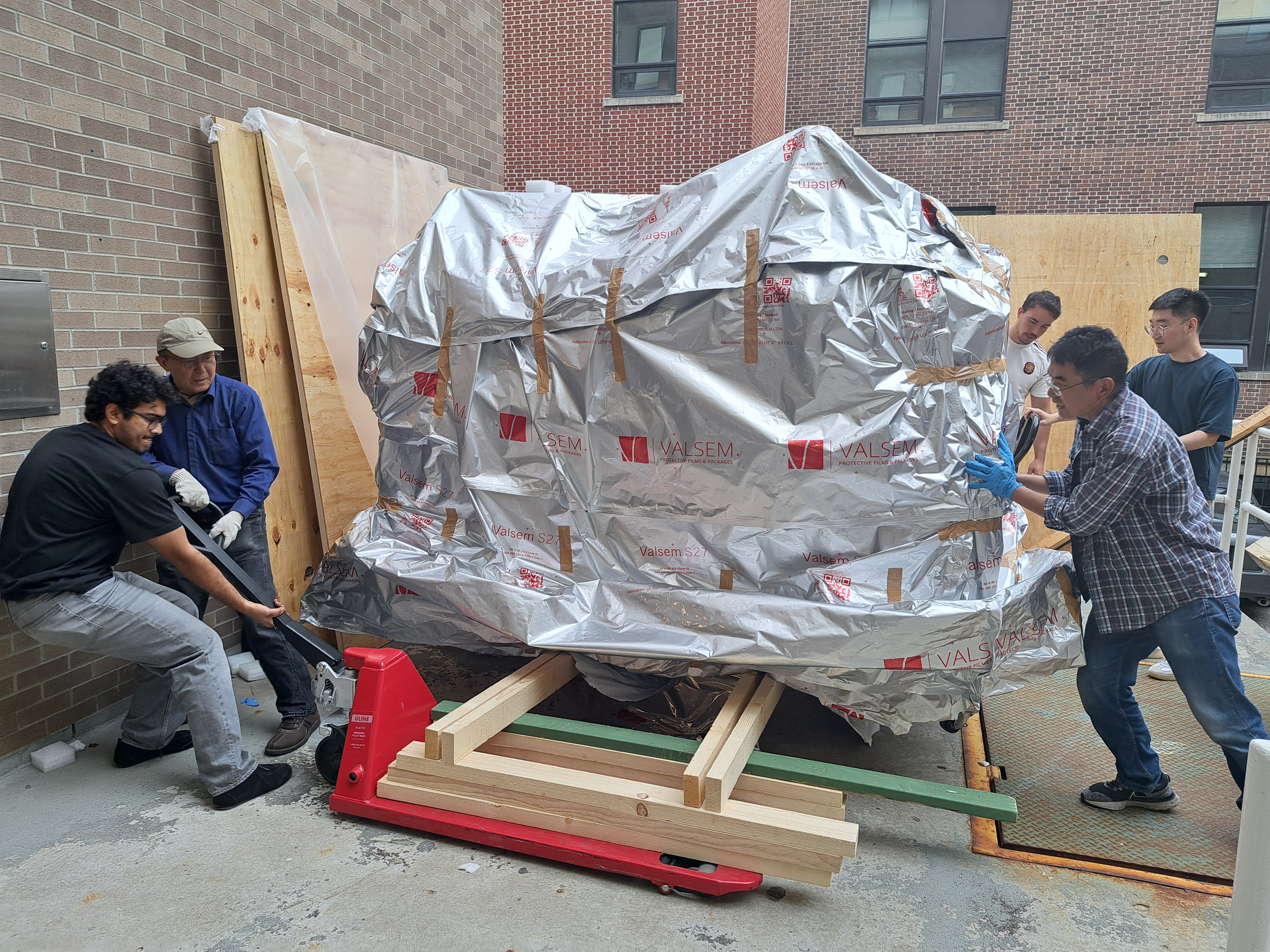 The team lowers the wrapped Plassys evaporator from its shipping support onto its wheels.